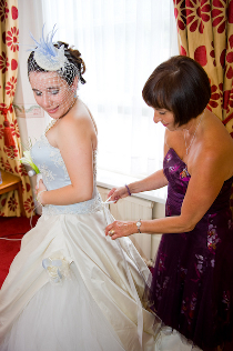 La mamma aiuta la figlia ad indossare l'abito da sposa