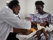 Un dottore sul campo visita un bambino grazie all'attività di AMREF