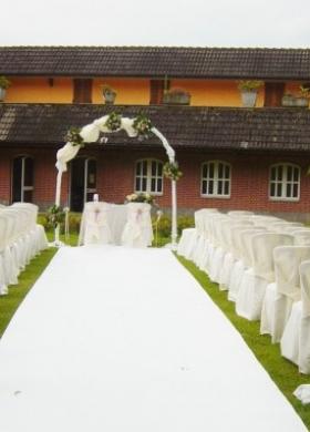Cerimonia di nozze all'aperto con arco di fiori e alti vasi sulla guida
