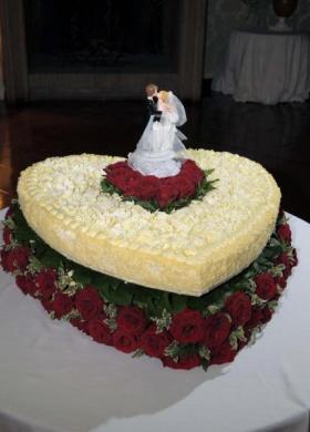 La torta di nozze a forma di cuore con rose rosse