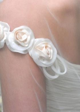Rose in tessuto applicate alla spallina dell'abito da sposa