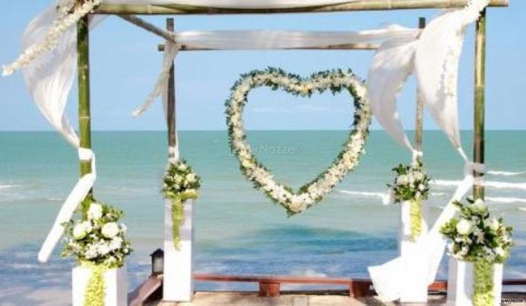 Scenografia con cuore floreale per un matrimonio in spiaggia