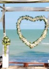 Scenografia con cuore floreale per un matrimonio in spiaggia