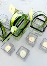 Particolare centrotavola creato con calle, candele e piccoli vasetto di vetro