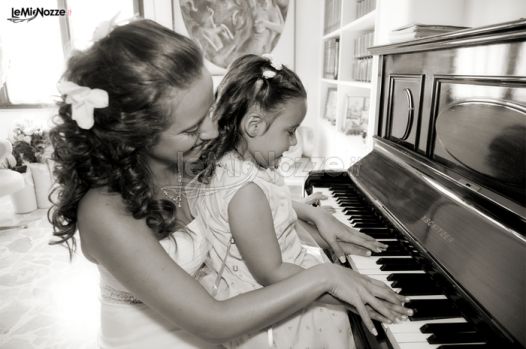 Foto della sposa che suona il piano con la damigella
