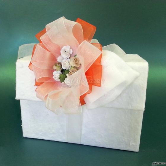 Scatola ricoperta in carta cotone con grande fiocco colorato e fiorellini in carta
