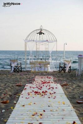 Allestimento della cerimonia in spiaggia con gazebo a forma di gabbia