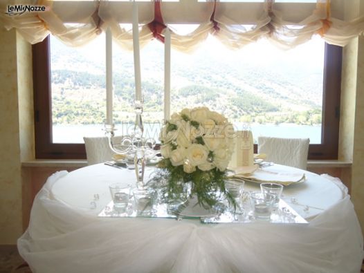 Il tavolo degli sposi allestito con rose bianche e candelabro