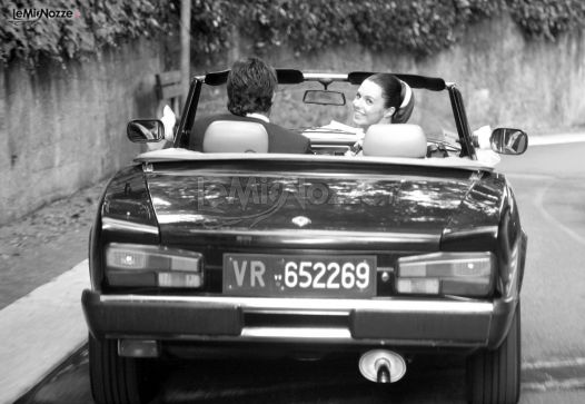 Foto in bianco e nero degli sposi sulla macchina d'epoca