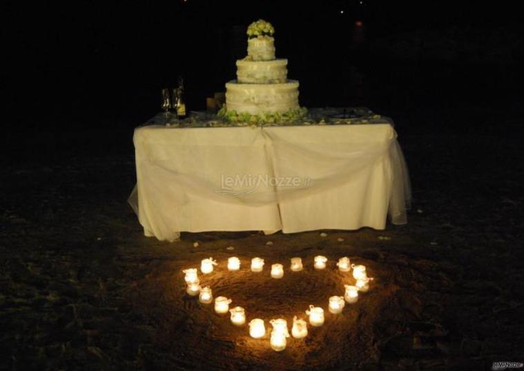 Torta nuziale in spiaggia con candele a forma di cuore