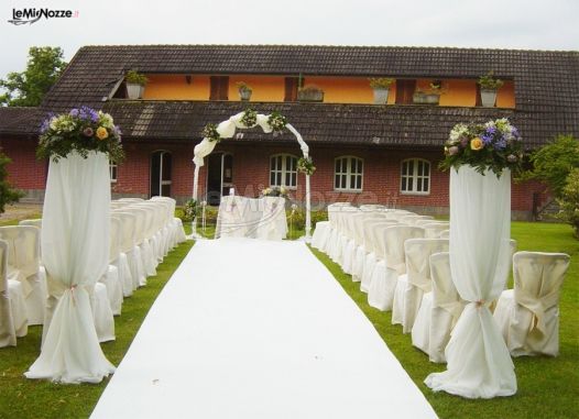 Cerimonia di nozze all'aperto con arco di fiori e alti vasi sulla guida