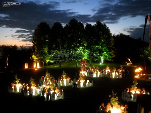 Ricevimento di nozze in giardino di sera con tavoli illuminati