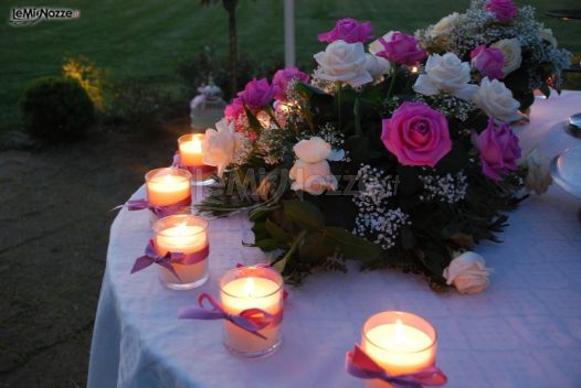 Allestimento con candele e rose per il tavolo della torta nuziale