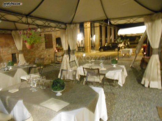 Sedie e tavoli allestiti per un banchetto di nozze serale "en plein air"